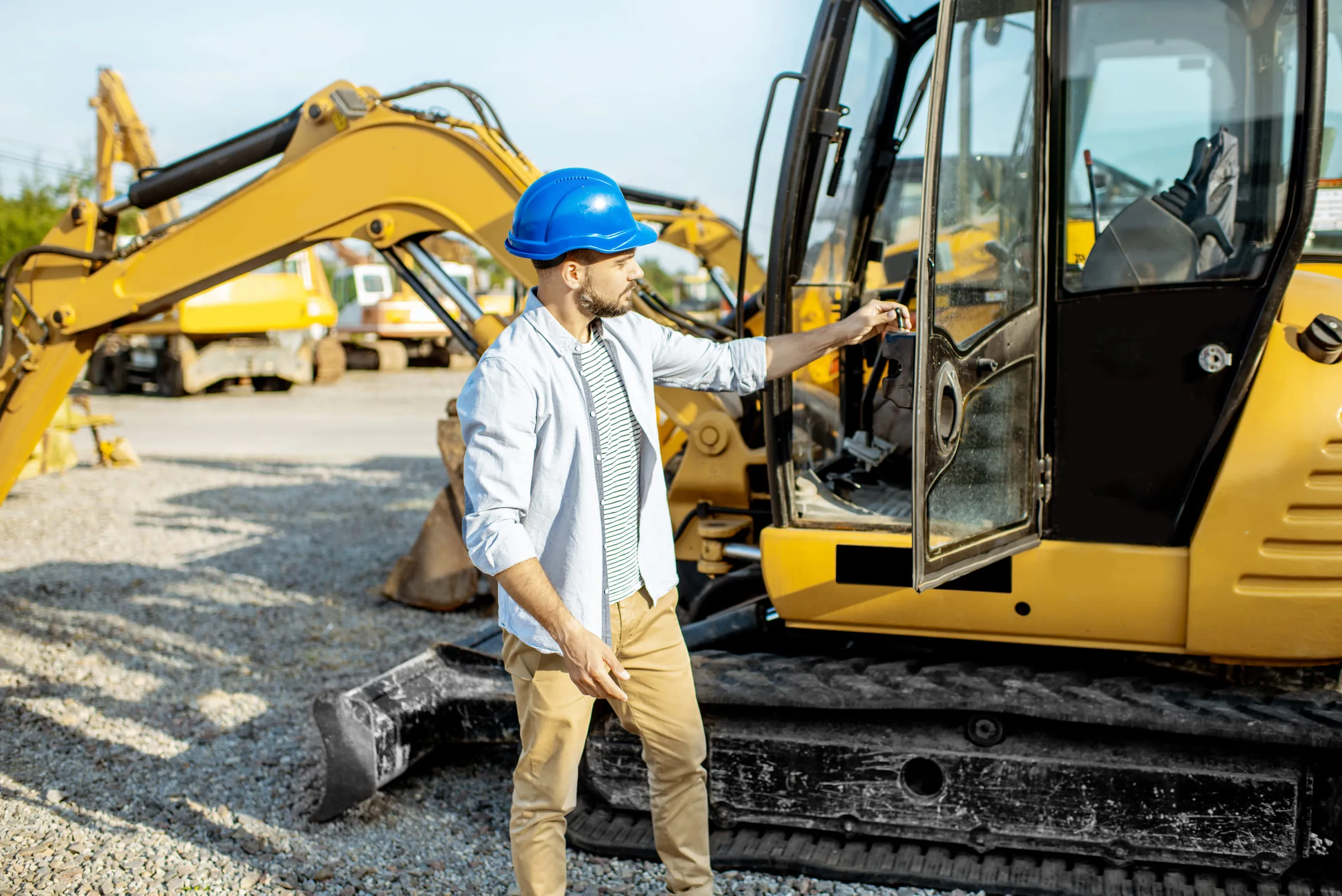Conducteur d’engins en casque devant une pelle hydraulique sur un chantier.