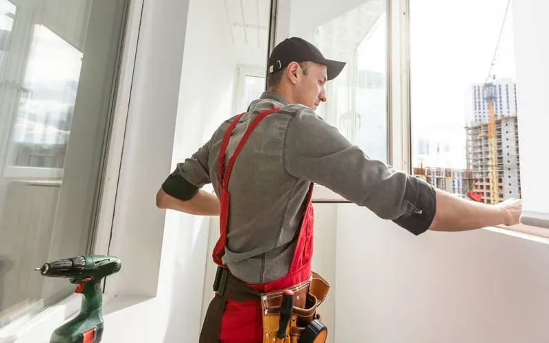Menuisier posant une fenêtre dans un logement en rénovation.